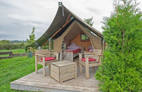 Glamping-accommodatie in safaritent op Inselcamping Kollersee, Rijnland-Palts, met houten terras en veel groen.