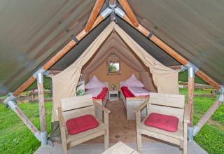 Hébergement glamping en tente safari à Inselcamping Kollersee, deux lits et chaises avec coussins rouges.