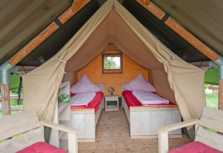 Binnenaanzicht van een glamping safaritent bij Inselcamping Kollersee met twee bedden en houten meubels.