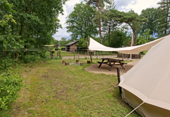 Basecamp Bell Zelt bei Thuysgrond in den Niederlanden mit Picknicktisch, Feuerstelle und Natur.