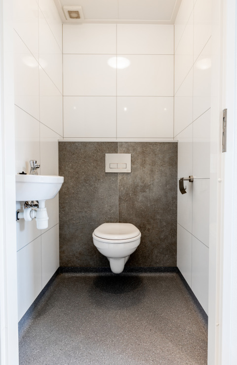 Modern restroom with wall-mounted toilet, small sink, and white tiles at Resort Mooi Bemelen in Netherlands.