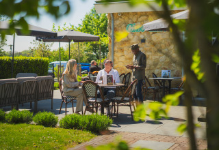 Café al aire libre en un sitio de glamping con dos personas pidiendo comida a un camarero.