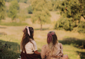Dos mujeres disfrutan de un picnic con pan y fruta en una manta en un alojamiento de glamping en la naturaleza.