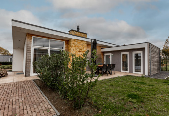 Moderne lodge med stor vinduesfacade og terrasse, beliggende i grøn have ved Ravenbosch med ildsted og bad.