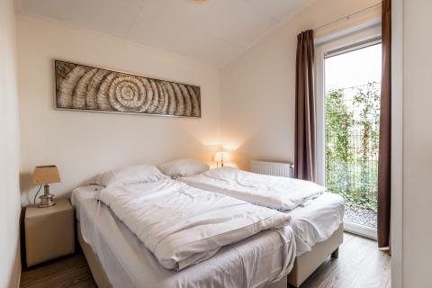 Slaapkamer met twee enkele bedden, moderne uitstraling en groot raam in Resort Mooi Bemelen, Nederland.