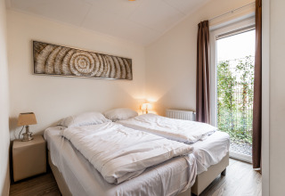 Slaapkamer met twee enkele bedden, moderne uitstraling en groot raam in Resort Mooi Bemelen, Nederland.
