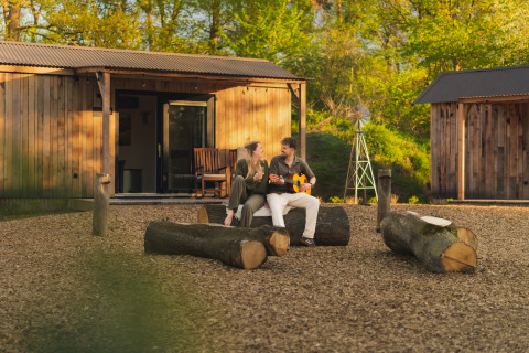 Couple relaxes outside the Nature house 'Barn' at Campsite Si-Es-An in the Netherlands, enjoying the outdoors.