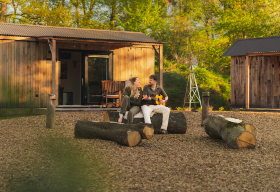 Stel ontspant buiten natuurhuis 'Barn' bij Campsite Si-Es-An in Nederland, genietend van de buitenlucht.