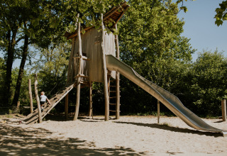 Estructura de parque infantil con tobogán en un entorno natural, tomada en un alojamiento glamping.