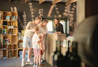 Familie tjekker ind i receptionen på et glamping-ophold, omgivet af naturinspireret indretning.