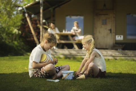 Zwei Kinder spielen auf dem Rasen vor einem Safarizelt am Campingplatz Si-Es-An in den Niederlanden.