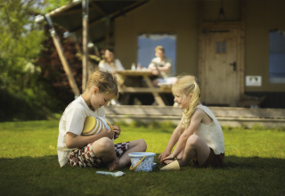 Zwei Kinder spielen auf dem Rasen vor einem Safarizelt am Campingplatz Si-Es-An in den Niederlanden.