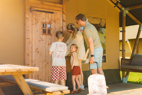 Familie vor einem Safarizelt auf dem Campingplatz Si-Es-An in den Niederlanden bereitet den Eintritt vor.