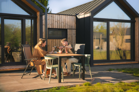 Twee personen eten samen aan een tafel voor een moderne Cosy Lodge op camping Si-Es-An in Nederland.