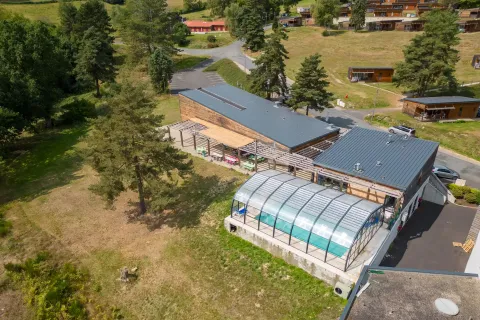 Luftaufnahme des Camping Holiday Park «Les Demeures du Lac» mit überdachtem Pool und Hütten in Auvergne-Rhône-Alpes.