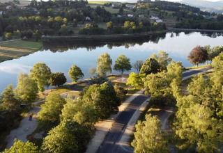 Luftaufnahme vom Camping Holiday Park Les Demeures du Lac mit See, Bäumen und Natur in Frankreich.