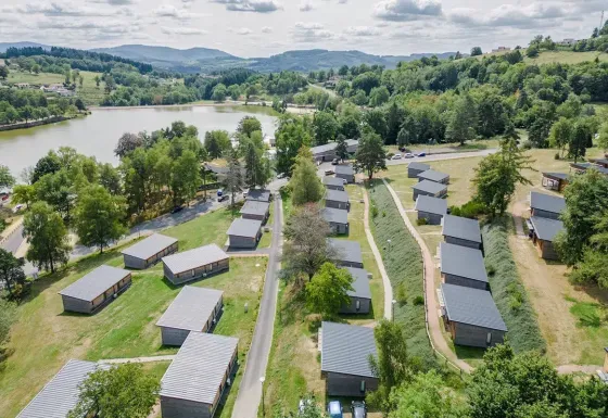 Luftaufnahme vom Ferienpark Les Demeures du Lac in Auvergne-Rhône-Alpes, Frankreich, mit See und Hügeln.