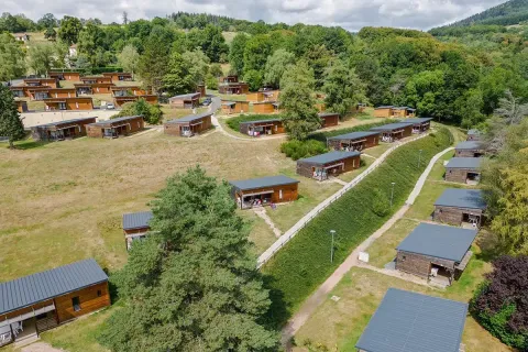 Vakantiepark met houten chalets op heuvelachtige grasvelden in Auvergne-Rhône-Alpes, Frankrijk.
