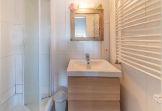 Modernes Bad im Le Chalet sous les Hetres in Belgien mit Dusche, Waschbecken und Holzspiegel.