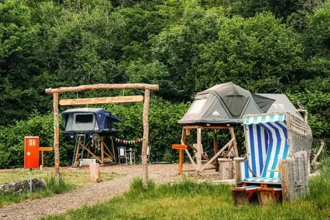 Glamping tents on raised platforms with seating at Dachzelt Dorf Sandstedt, a glamping site in Germany.