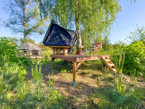 Unikt glamping-sted med tagtelt på træterrasse i Dachzelt Dorf Sandstedt omgivet af natur og solskin.