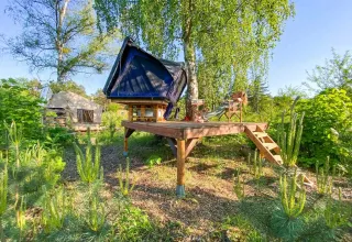 Glamping accommodatie met daktent op houten platform bij Dachzelt Dorf Sandstedt te midden van groene natuur.
