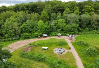 Aerial view of Dachzelt Dorf Sandstedt glamping site surrounded by lush greenery and forest trails.
