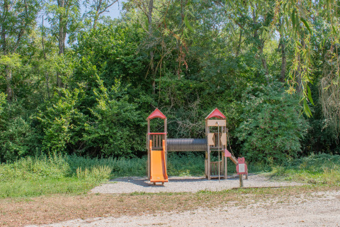 Spielplatz im Ferienpark mit Rutsche und Spielturm, umgeben von Bäumen, perfekt für Glamping.