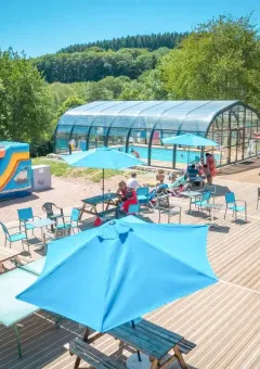 Area esterna del Camping Paradis Les Chanterelles in Auvergne-Rhône-Alpes con piscina coperta e giochi per bambini.
