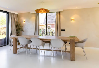 Sala da pranzo nella Forest villa «Zoethout» a De Kremmer, Paesi Bassi, tavolo in legno e sedie bianche.