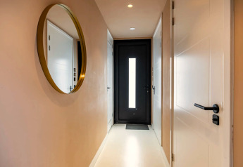 Moderner Flur mit rundem Spiegel, weißem Interieur und schwarzer Haustür in Forest villa «Zoethout», De Kremmer, Niederlande.