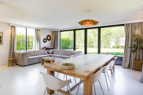 Lichte woon- en eetkamer in Forest villa «Zoethout», De Kremmer, Nederland, met grote ramen en tuinzicht.