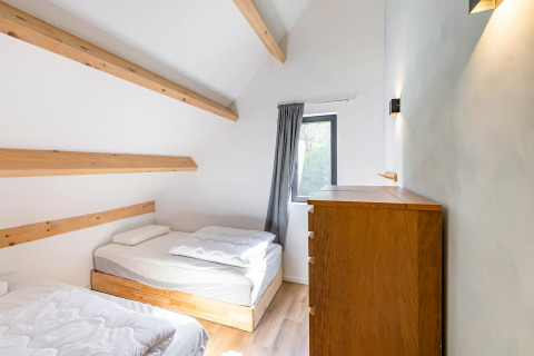 Lichte kamer met twee eenpersoonsbedden, houten balken en kast in Forest villa «Zoethout» in De Kremmer.