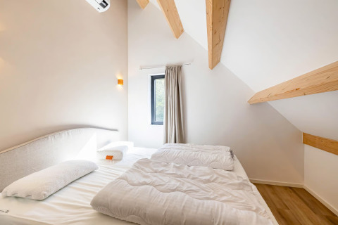 Slaapkamer met schuin plafond en houten balken in Forest villa «Zoethout» bij De Kremmer, Nederland.