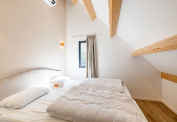 Camera da letto con soffitto inclinato e travi in legno presso Forest villa «Zoethout» a De Kremmer, Paesi Bassi.