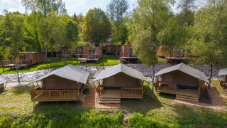 Luxe safaritenten en houten chalets omgeven door groen, ideaal voor glamping en rustgevende uitjes.