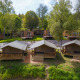 Tentes safari et cabanes en bois entourées de verdure, parfaites pour un séjour de glamping reposant.