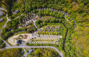 Luchtfoto van de Safari Tent camping met tenten, huisjes, parkeerplaatsen en omringend bos.