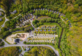 Vista aérea del camping Safari Tent con tiendas, cabañas, aparcamiento y bosque circundante.