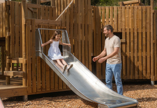 Un homme accompagne une enfant sur un toboggan au terrain de jeux du Safari Tent à Hameau de l'Ourthe, Belgique.