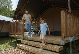 Un uomo e un ragazzo scendono i gradini di una tenda safari presso Hameau de l'Ourthe in Belgio.
