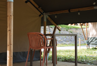 Safari-Zelt mit Holzterrasse, Tisch und Stuhl im Hameau de l'Ourthe in Belgien, perfekt für Camping.