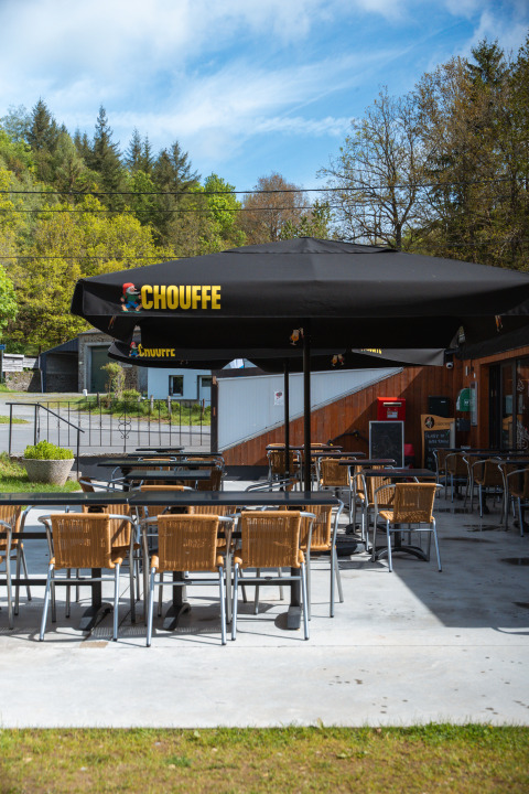 Outdoor seating area at the Safari Tent at Hameau de l'Ourthe, Belgium, with empty chairs and tables.
