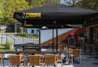 Outdoor seating area at the Safari Tent at Hameau de l'Ourthe, Belgium, with empty chairs and tables.