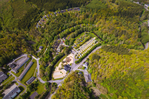 Aerial view of the Safari Tent at Hameau de l'Ourthe in Belgium, surrounded by forests and winding roads.