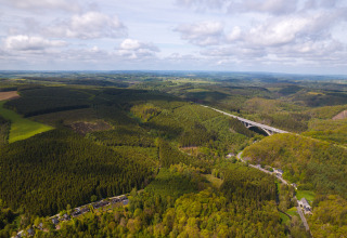 Vista aerea di fitte foreste verdi e un ponte vicino alla Safari Tent ad Hameau de l'Ourthe, Belgio.
