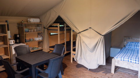 Binnenzicht van een safaritent op Camping Emmen in Nederland met bedden, keukenhoek en eetruimte.