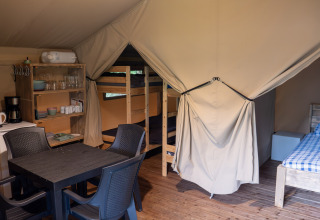 Binnenzicht van een safaritent op Camping Emmen in Nederland met bedden, keukenhoek en eetruimte.