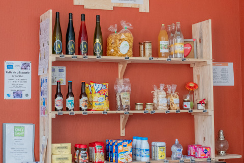 Houten rek met streekproducten en dranken bij de receptie van Onlycamp Camping l'Orée d'Alsace, Grand Est, Frankrijk.
