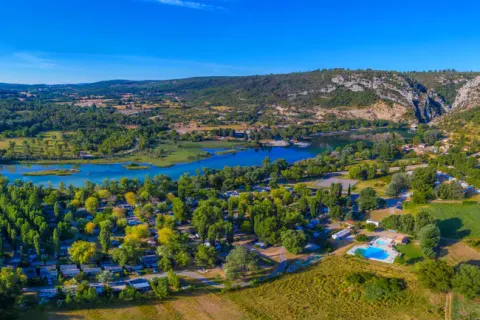 Luftaufnahme vom Seasonova Camping Les Prés du Verdon mit Fluss, Pool und Hügeln in der Provence, Frankreich.